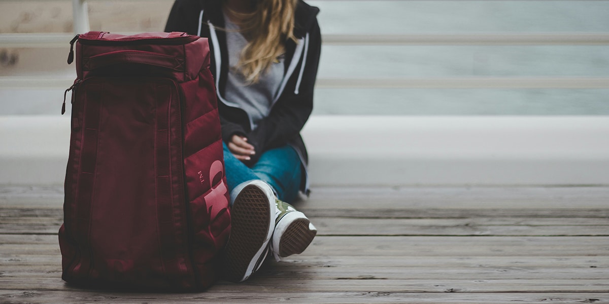 woman sitting with a backpack full of her belongings.