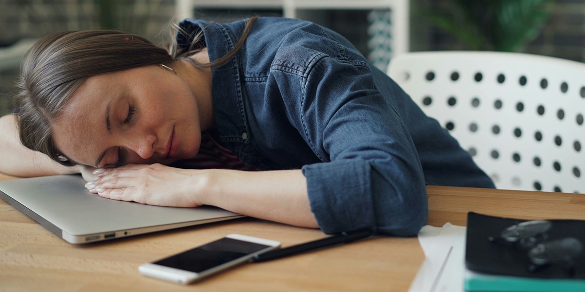 woman resting her head on a desk, being sleepy.