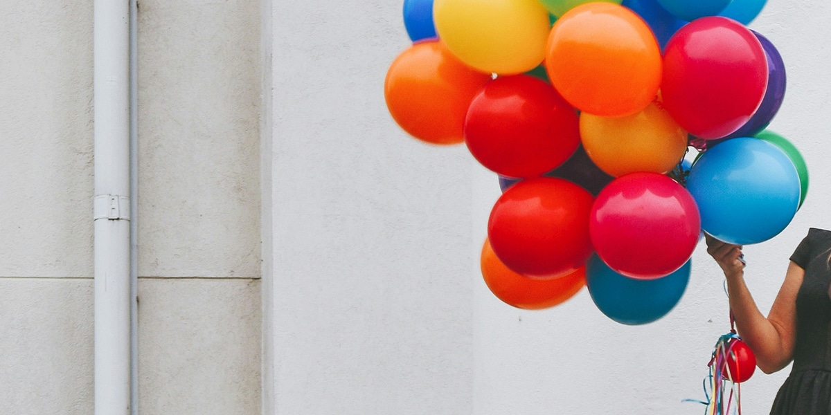 woman holding multiple multicolor balloons