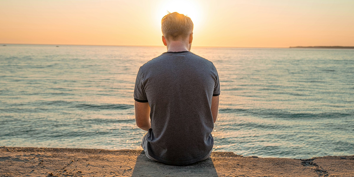 man sitting at a beach, reflecting