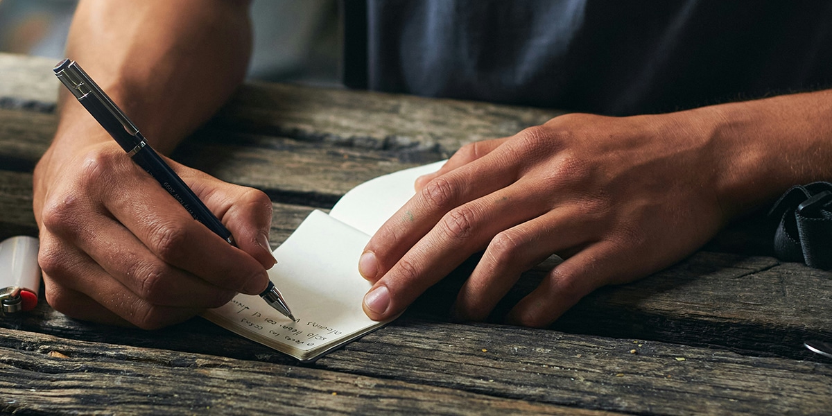 hand writing a note onto a piece of paper.