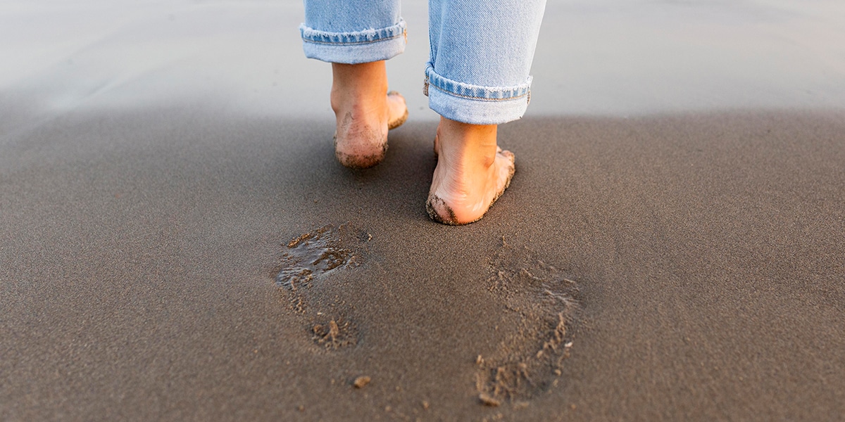 person making footprints in the sand