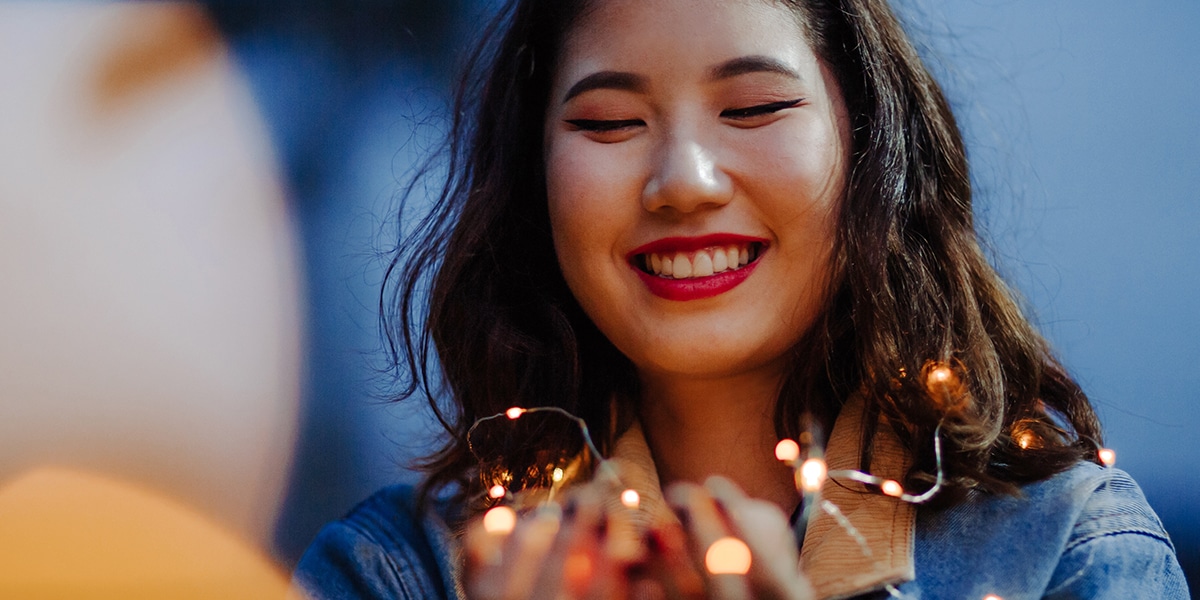 woman praying while holding lights in her hands