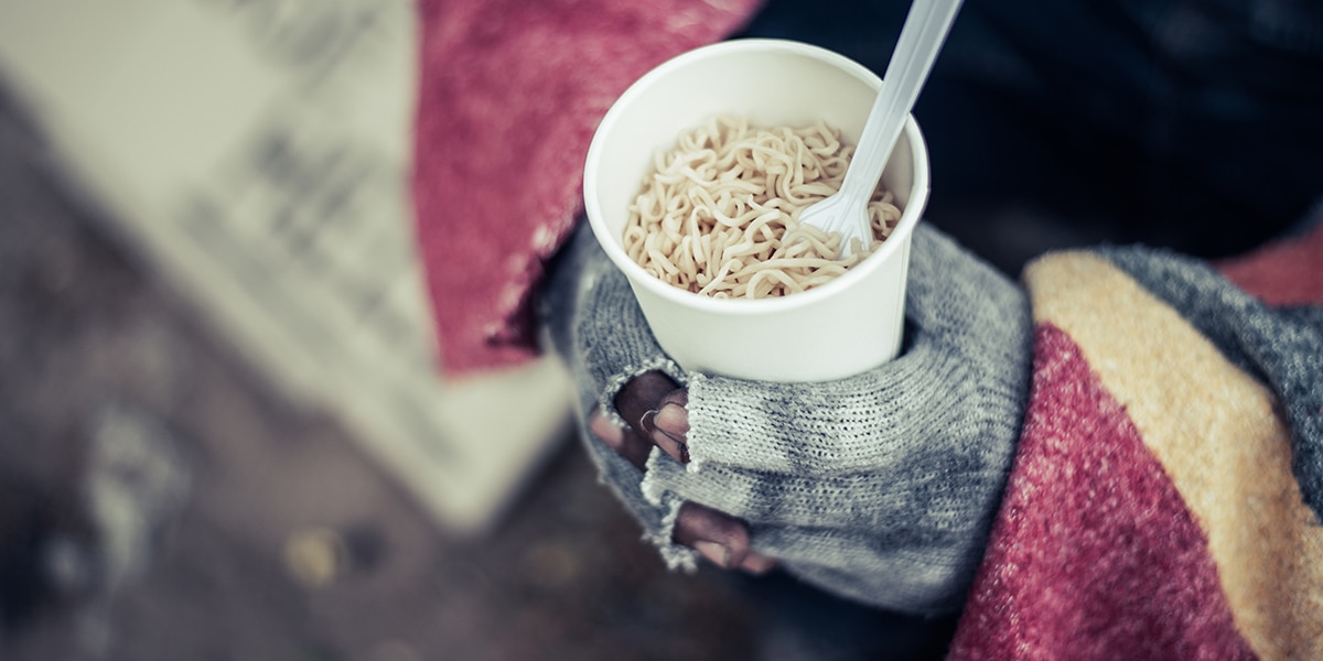 homeless person hold a cup filled with cuddles in his hands.