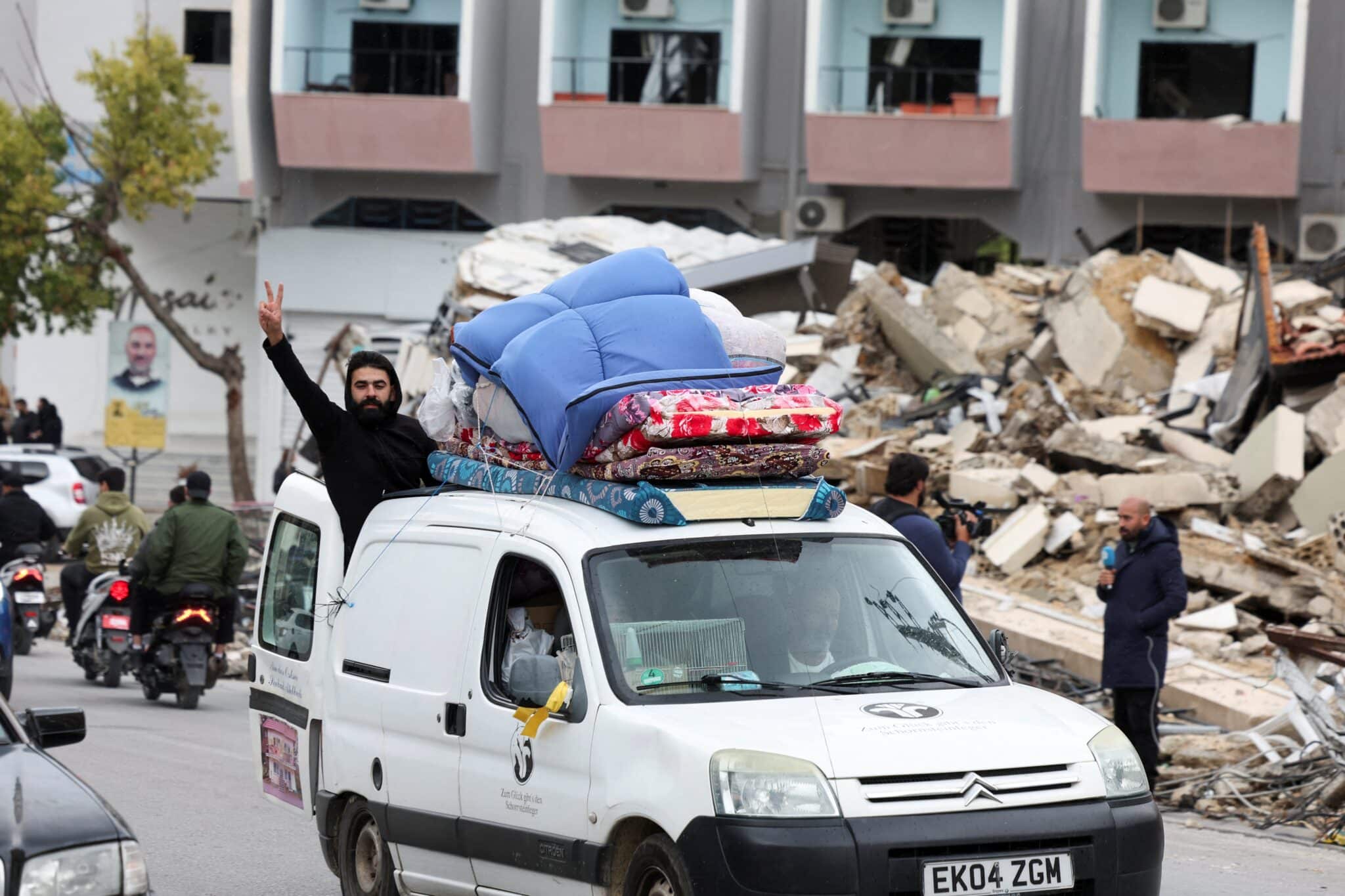 A man gives the victory sign from a vehicle as it drives past rubble in Al Haush, Lebanon, Nov. 27, 2024, after a ceasefire between Israel and Hezbollah took effect.