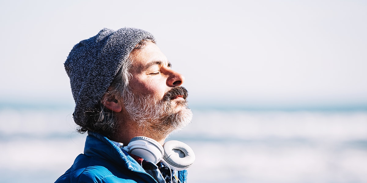 man with eyes closed, taking a deep breath while quietly meditating