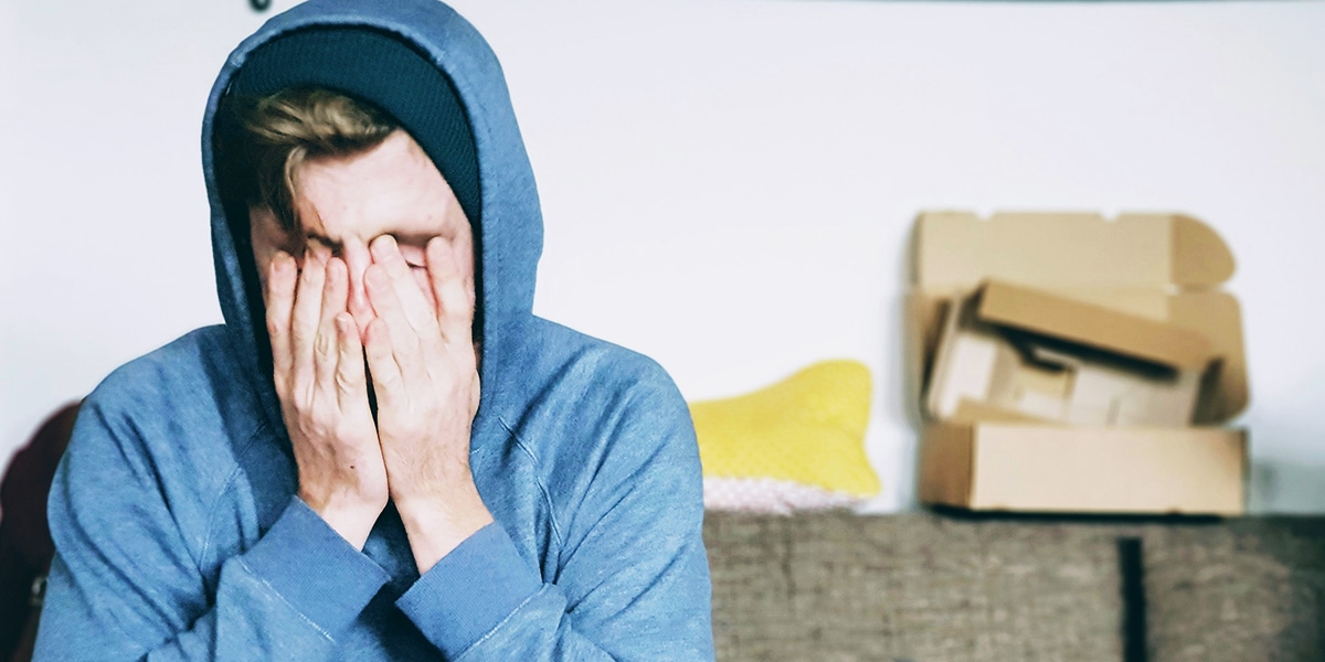 A man feeling overwhelmed has his face covered with his hands