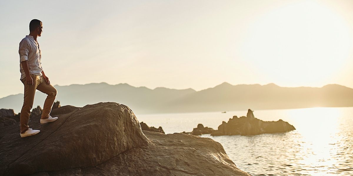 man standing on a rock in a bay.