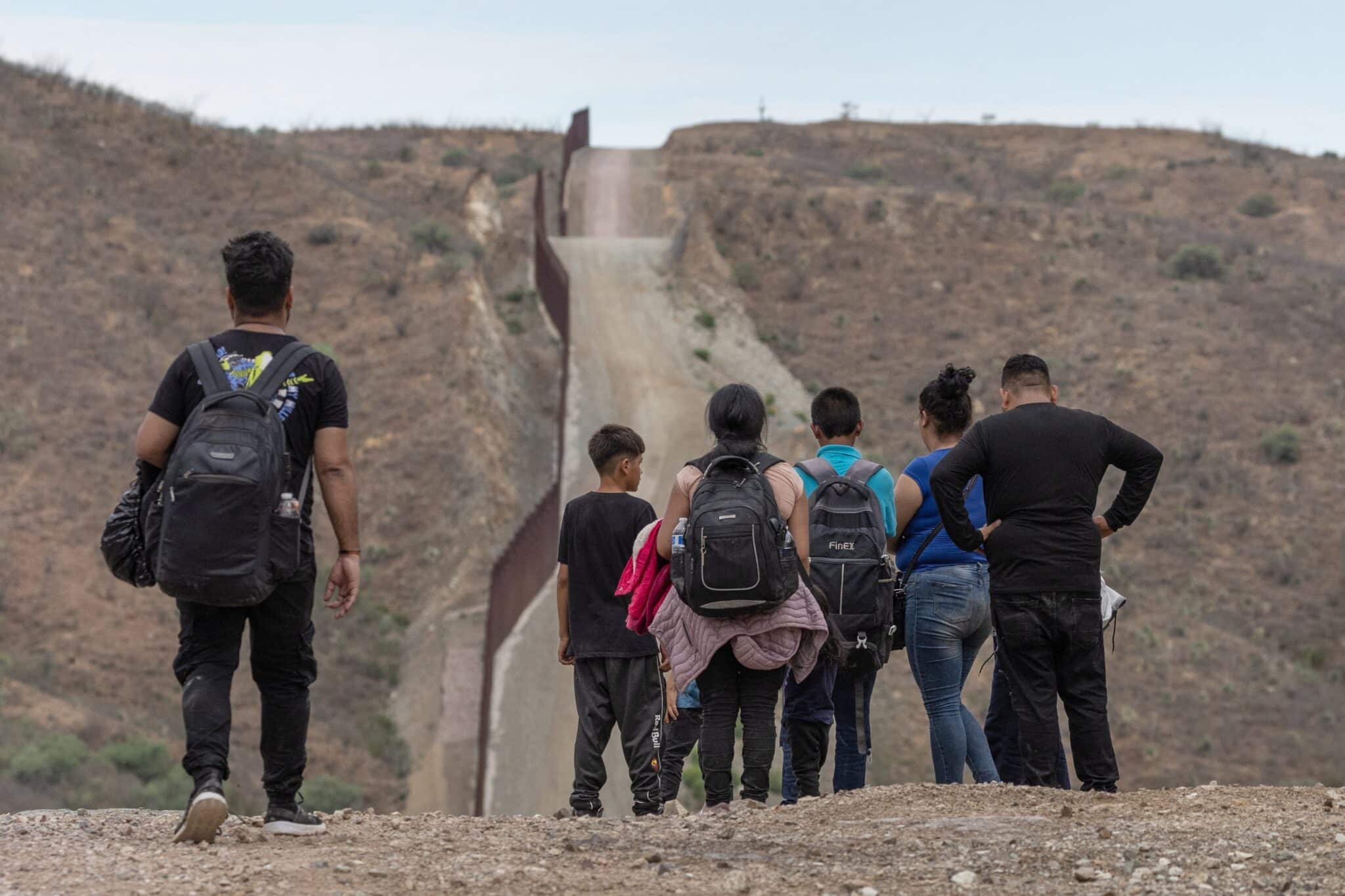 The wall at the U.S.-Mexico border is seen in the background as migrants from South and Central America look to surrender to immigration officials after crossing into the United States from Mexico in Ruby, Ariz., June 24, 2024. (OSV News photo/Adrees Latif, Reuters)