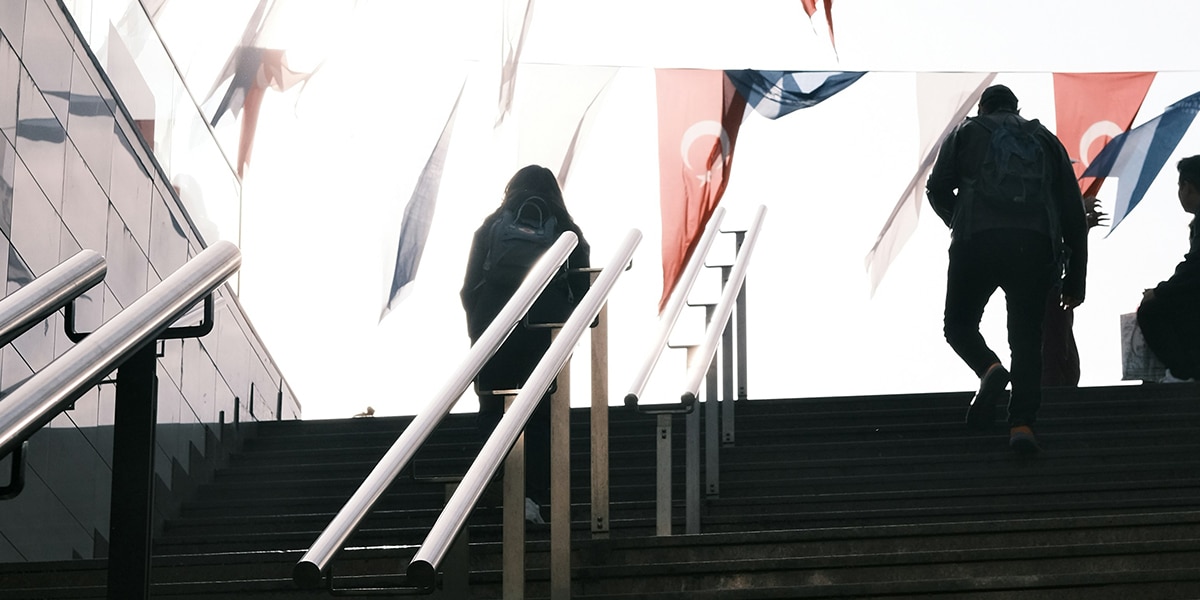 People walking up stairs in Istanbul, Turkey, being surrounded by Turkish flags.