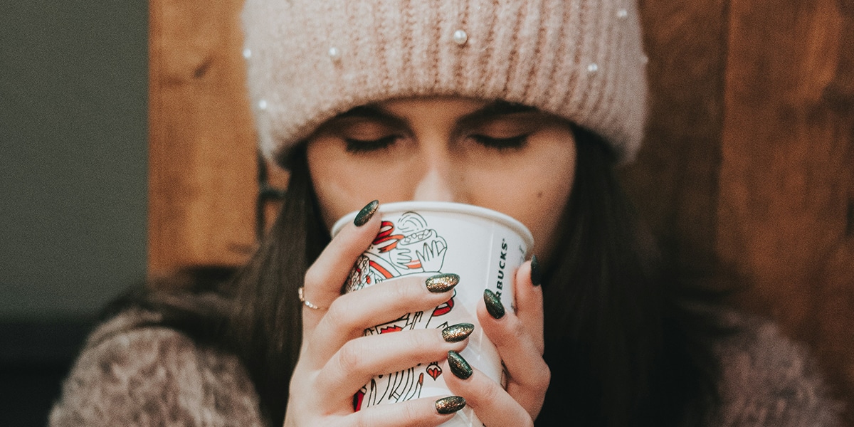 woman drinking from her warm coffee with a grateful expression on her face.