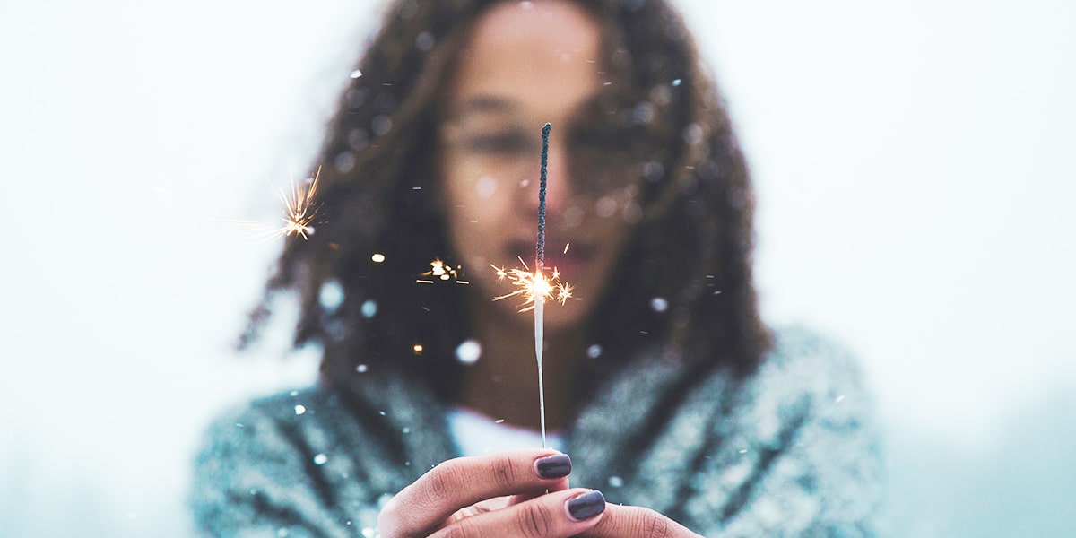 woman holding a sparkler while standing outside in the cold