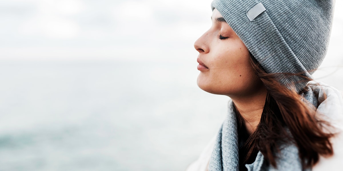 woman standing quietly, eyes closed, meditating.