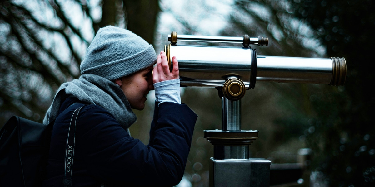 woman looking through big binoculars.