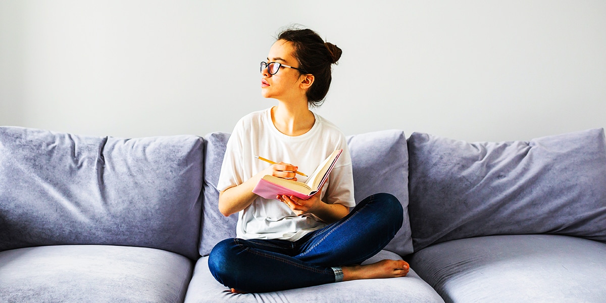 woman sitting on a couch reading a book in a minimalist room.