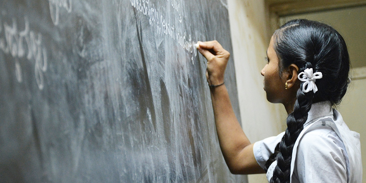 woman teacher writing on chalk board