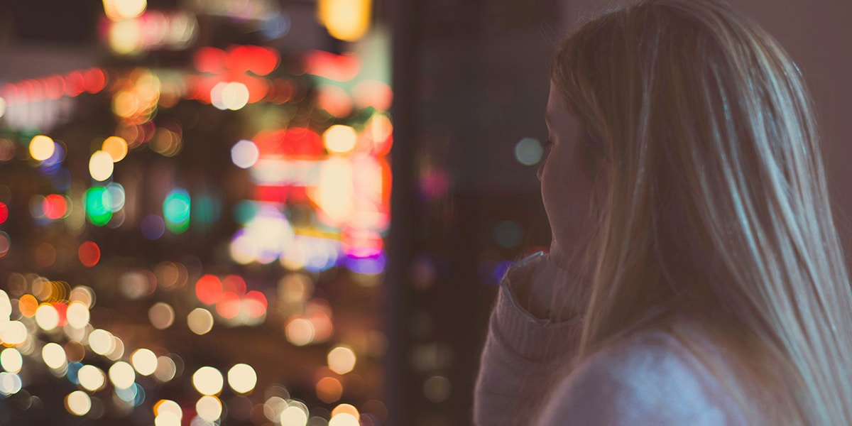 woman looking at lights outside a window