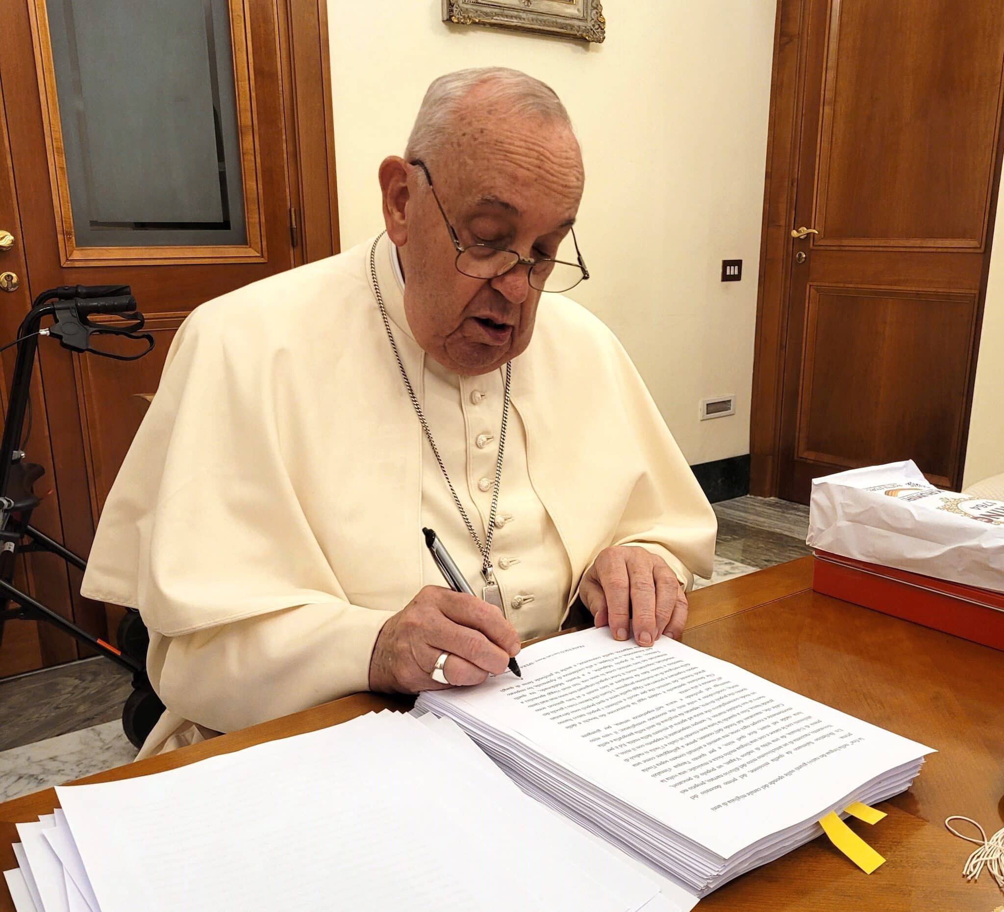 Pope Francis reviews and initials each page of the manuscript of "Hope: The Autobiography" Aug. 9, 2024, in his Vatican residence, the Domus Sanctae Marthae.