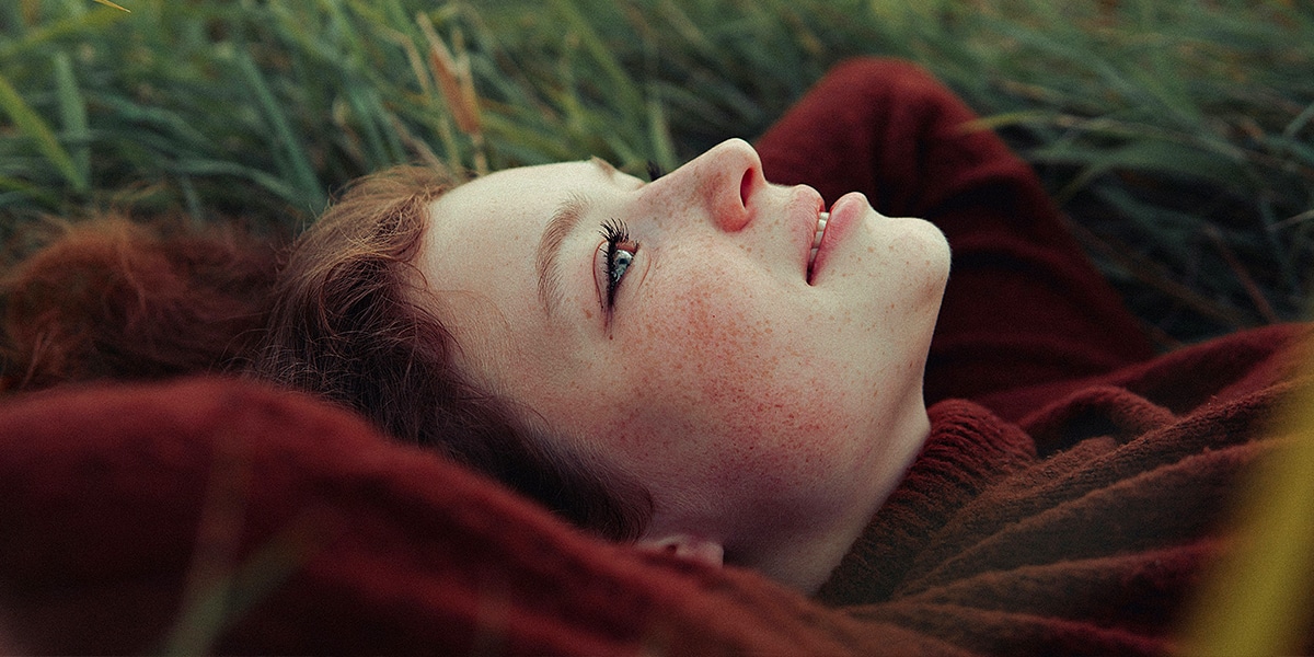 girl laying on her back in a field, looking upwards