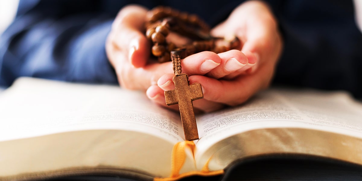 hands holding a rosary with a wooden cross