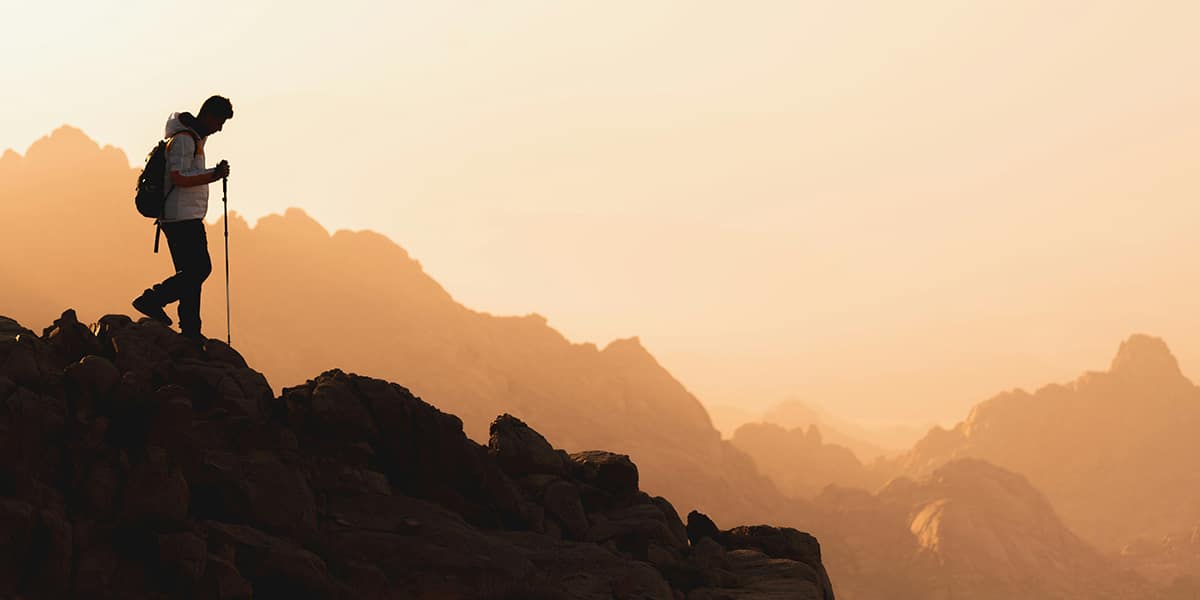 man hiking in the mountains during sunrise