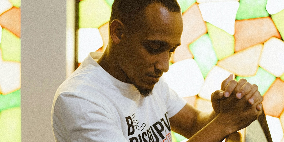 man praying in church with folded hands