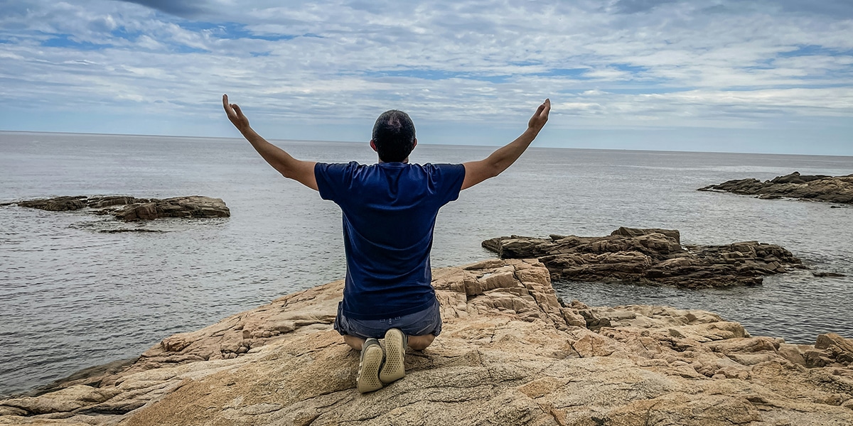 man kneeling with hands raised while praying