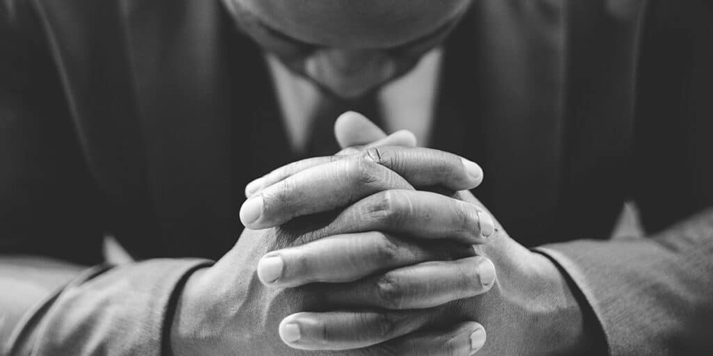 man praying with folded hands