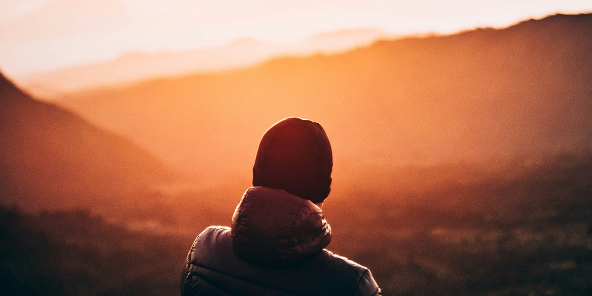 person watching a sunrise, surrounded by warm light