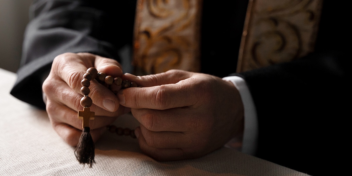 a priest holding a rosary while praying