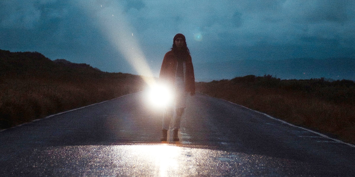 young woman shining a flashlight in the darkness