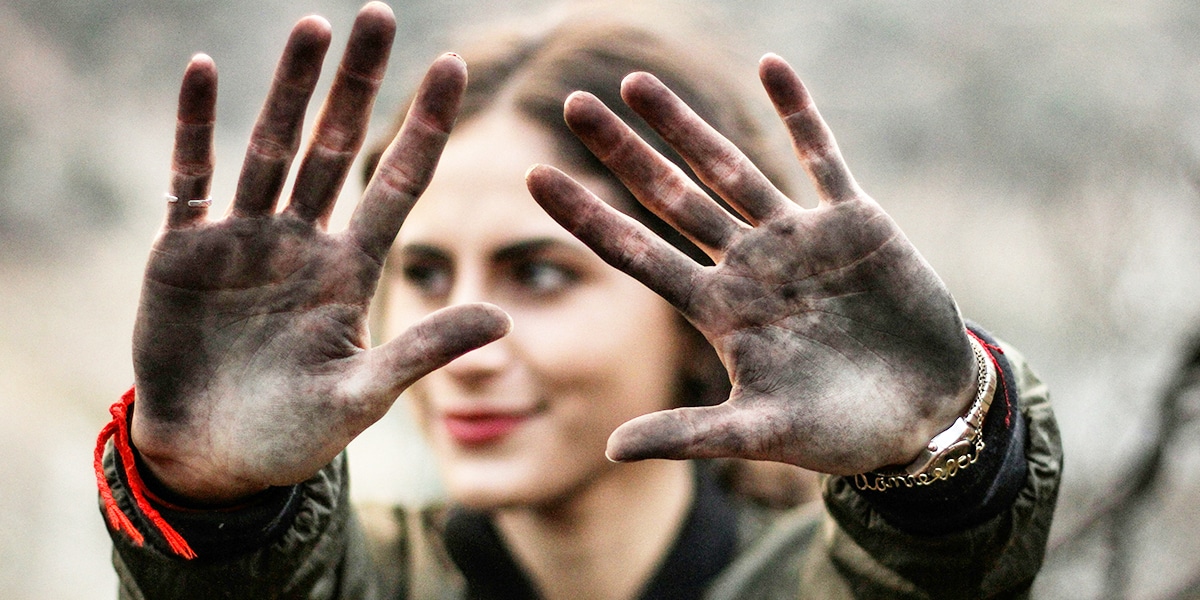 woman holding up her dirty hands from working in the fields.