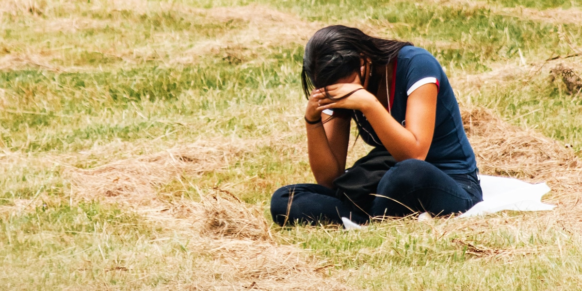 woman sitting in a field, praying