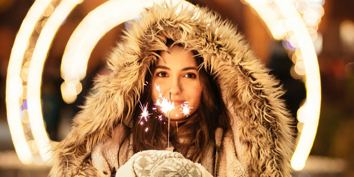 woman wearing a winter coat in the cold, holding a sparkler