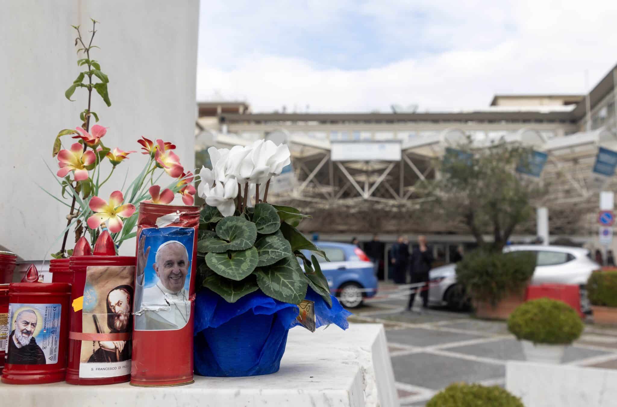 Flowers and votive candles sit at the base of a statue of St. John Paul II outside Rome’s Gemelli hospital Feb. 18, 2025, where Pope Francis is a patient. (CNS photo/Pablo Esparza)