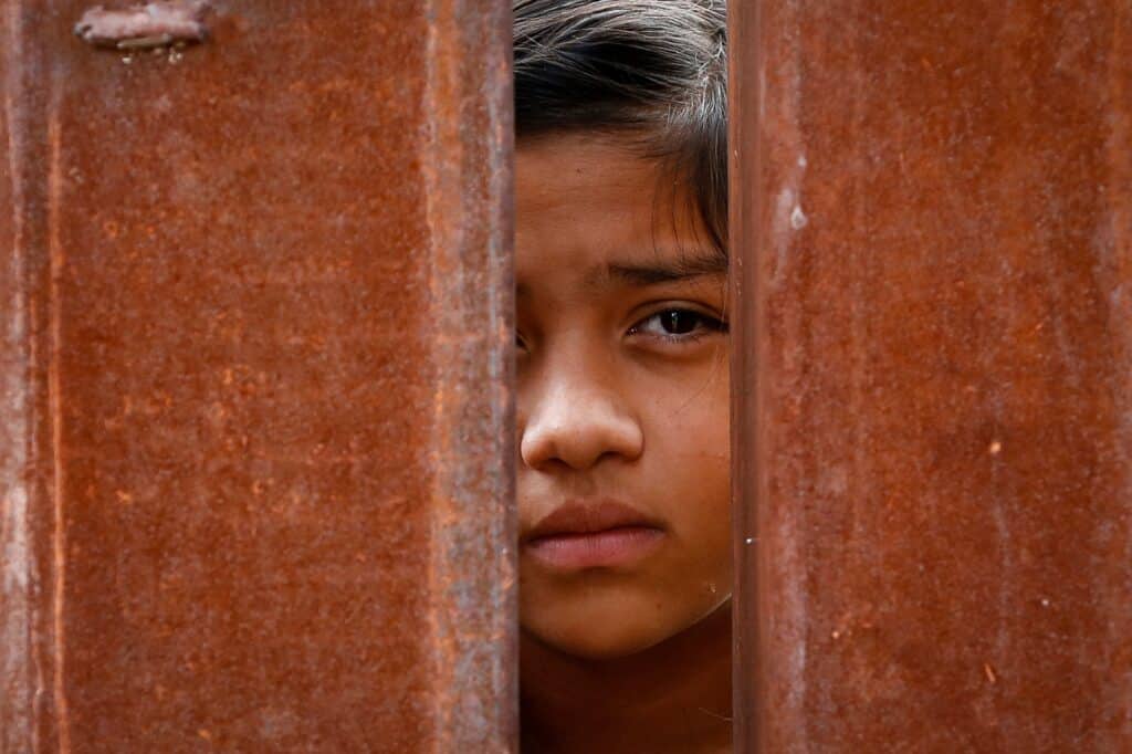 A Mexican girl peers through the fence during Mass at the international border in Nogales, Ariz., Oct. 23. Dioceses Without Borders, an effort of Mexico's Nogales Diocese and the U.S. dioceses of Phoenix and Tucson, Ariz., organized the liturgy celebrated on both sides of the U.S.-Mexico border. (CNS photo/Nancy Wiechec) See BORDER-MASS-PIERRE Oct. 24, 2016.