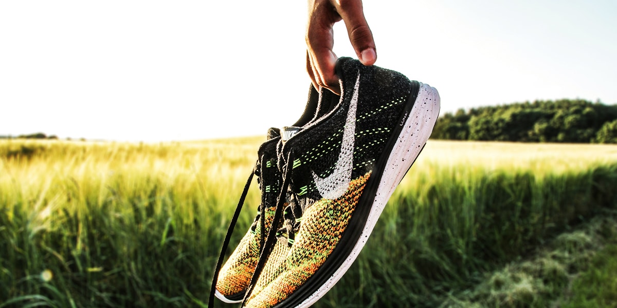 hands holding running shoes in a field