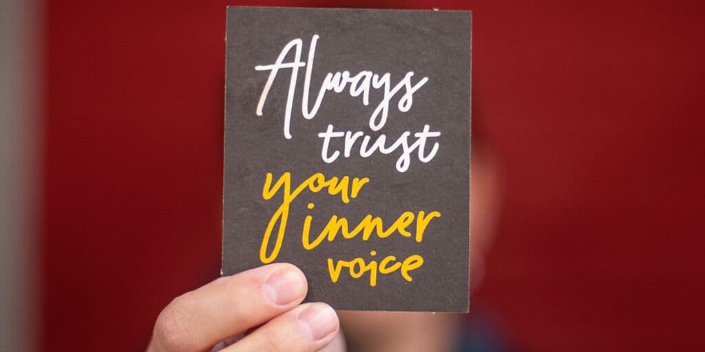 hand holding a sign with the words "always trust your inner voice"