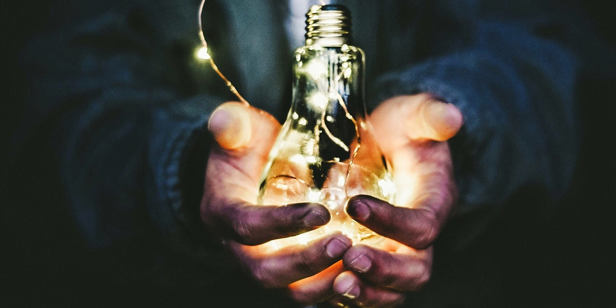 hands holding a glowing lightbulb