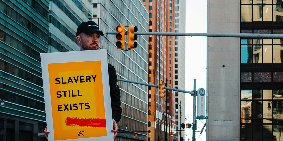 man holding sign with the words "Slavery Still Exists"