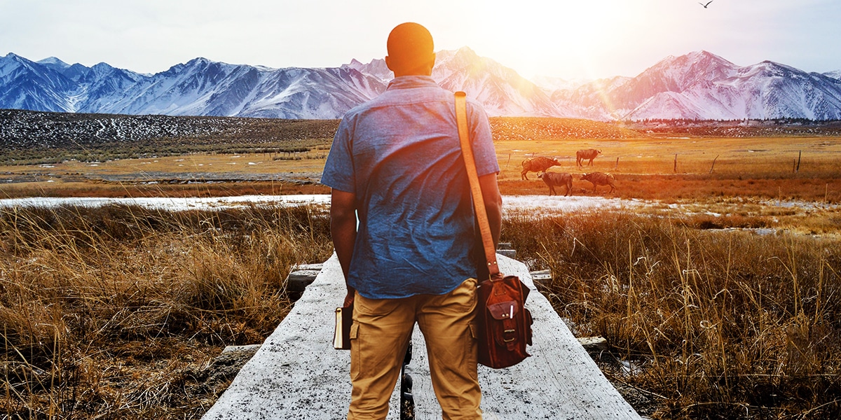 man walking on a wooden path while holding his Bible