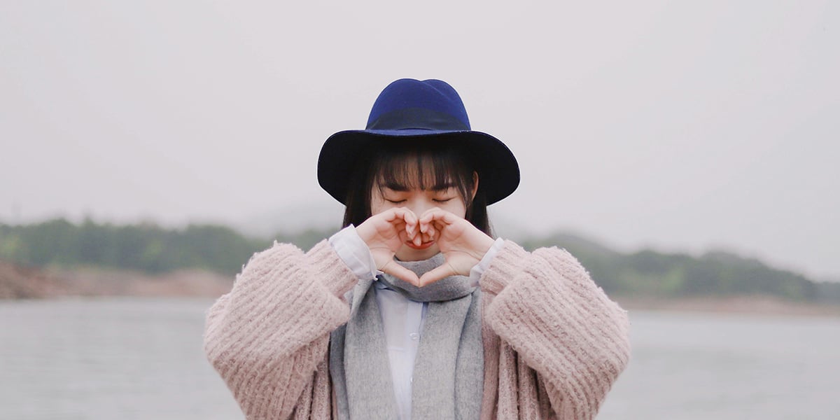 woman using her hands to form a heart