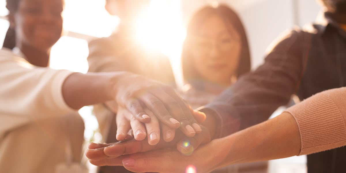 Group of diverse people unified stacking hands on top of each other as a symbol of teamwork