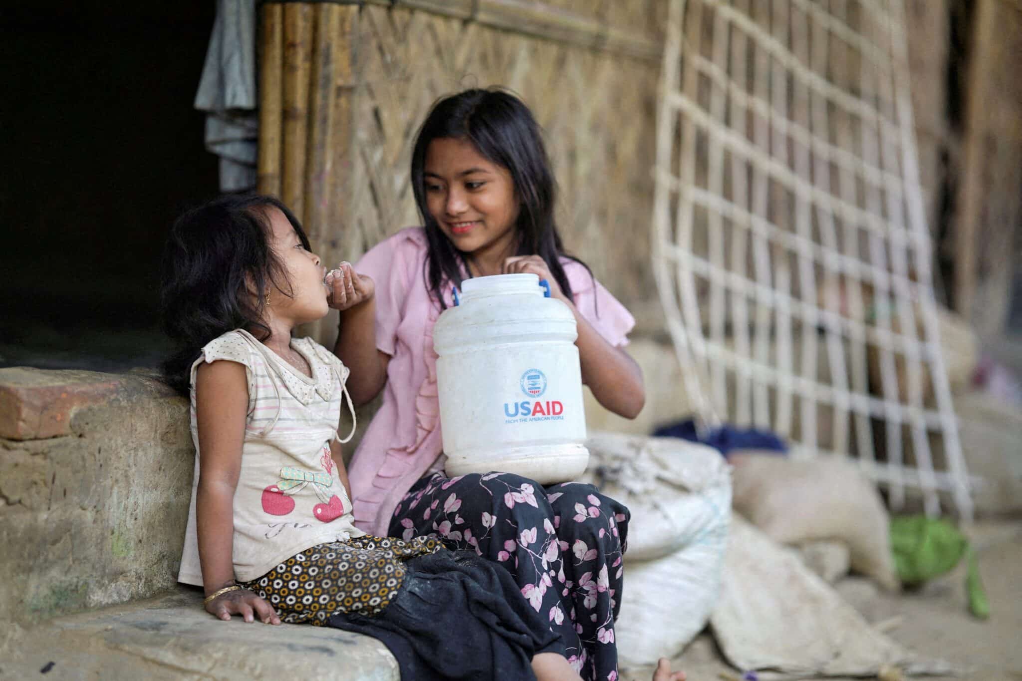 A Rohingya girl feeds a child from a jar with the USAID logo on it, at a refugee camp in Cox's Bazar, Bangladesh, Feb. 11, 2025.