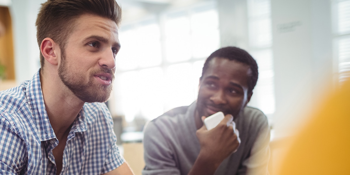 group of men in conversation, one man listening and one man talking