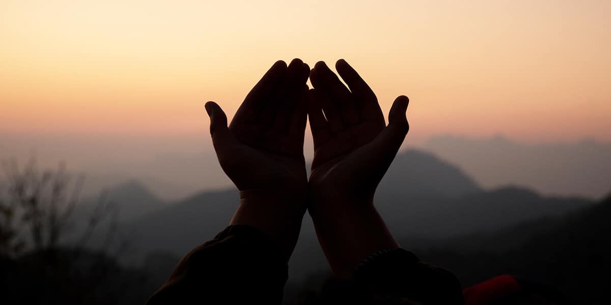 hands peaceful in worship with a sunrise in the background