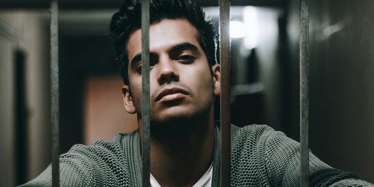 man with attitude on his face behind metal bars