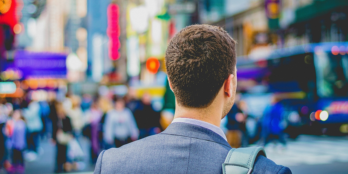 man waiting for a bus in the busy rush hour traffic with lots of people