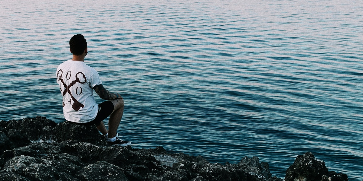 man sitting by water in silence