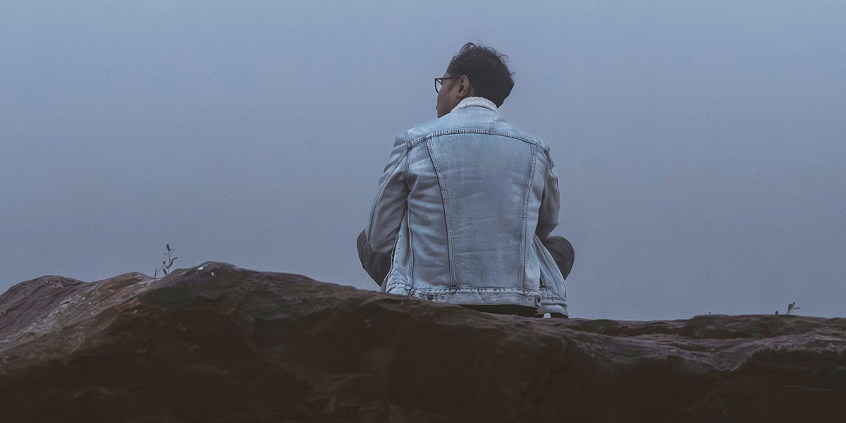 man sitting quiet on a rock in fog